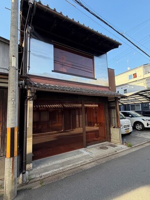 Ein Gebäude im traditionellen japanischen Baustil, mit einem hölzernen Eingang und einer großen Werbetafel darüber.