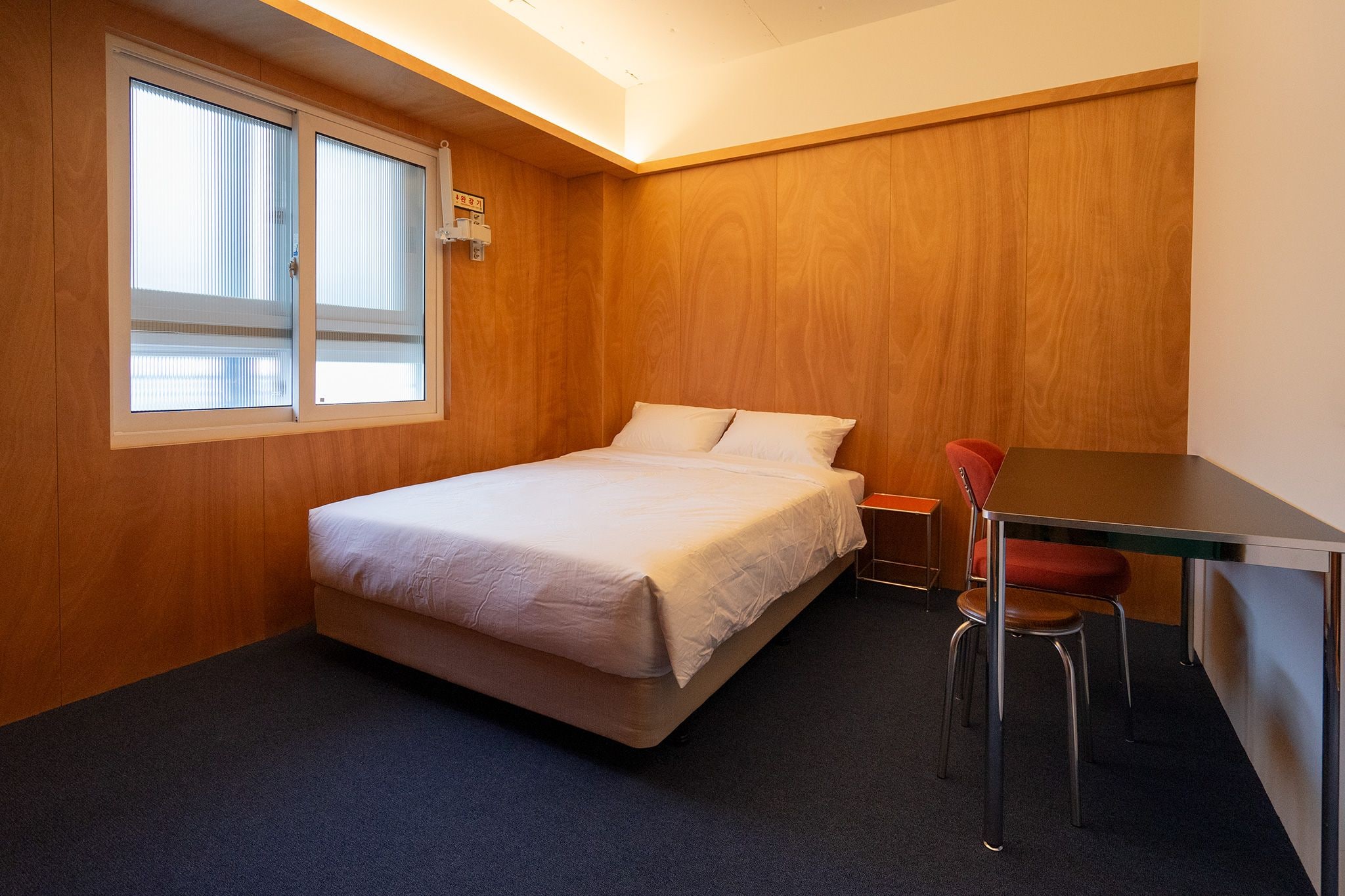 Una habitación pequeña y ordenada con una cama, una mesa y una silla.