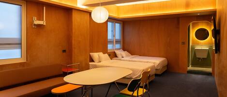 Una habitación de hotel con una cama, una mesa redonda, un banco y un baño pequeño.