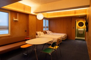 Una habitación de hotel con una cama, una mesa redonda, un banco y un baño pequeño.