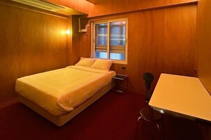Una habitación con una cama, una mesita y una ventana.