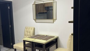 Un comedor con una mesa y sillas, un espejo montado en la pared y una puerta.