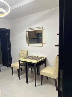 A dining area with a table and chairs, a wall-mounted mirror, and a door. - Cozy 1-bedroom studio in enchanting Santa Cruz de la Sierra with AC (Santa Cruz de la Sierra)