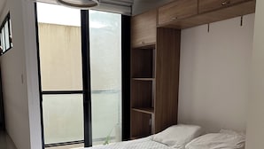 Un dormitorio con cama, armario y una ventana grande.