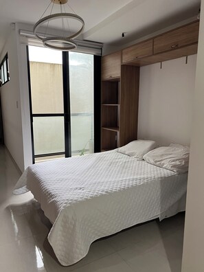 A bedroom with a bed, a wardrobe, and a large window. - Cozy 1-bedroom studio in enchanting Santa Cruz de la Sierra with AC (Santa Cruz de la Sierra)