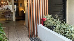 Entrada moderna de edificio con diseño de listones de madera, un camino adoquinado y una jardinera con plantas.