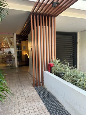 A modern building entrance with a wooden slatted design, a tiled pathway, and a small planter with plants. - Cozy 1-bedroom studio in enchanting Santa Cruz de la Sierra with AC (Santa Cruz de la Sierra)