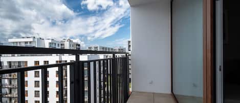 A balcony with a view of adjacent buildings and a clear sky.