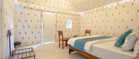 Una habitación con carpa, una cama, una silla y una pequeña mesa.