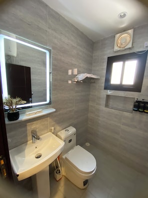 A modern bathroom with a sink, toilet, and mirror. - Studio Apartment in Al Hamdaniyah- J14 (Jeddah)