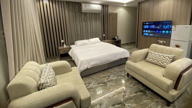 A modern hotel room with a bed, two sofas, a TV, and an air conditioning unit. - Studio Apartment in Al Hamdaniyah- J14 (Jeddah)