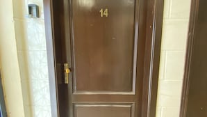 A brown door with the number 14, a small step leading up to it, and a wall-mounted device to the left. - Studio Apartment in Al Hamdaniyah- J14 (Jeddah)