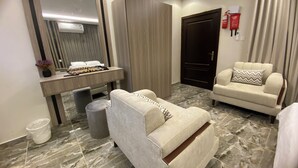 A modern hotel room with a bed, a sofa, a desk with a mirror, and a door. - Studio Apartment in Al Hamdaniyah- J14 (Jeddah)