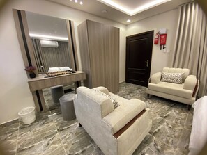 A modern hotel room with a bed, a sofa, a desk with a mirror, and a door. - Studio Apartment in Al Hamdaniyah- J14 (Jeddah)