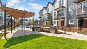 Un complexe résidentiel doté d’un patio couvert, d’un barbecue extérieur et d’une piscine.
