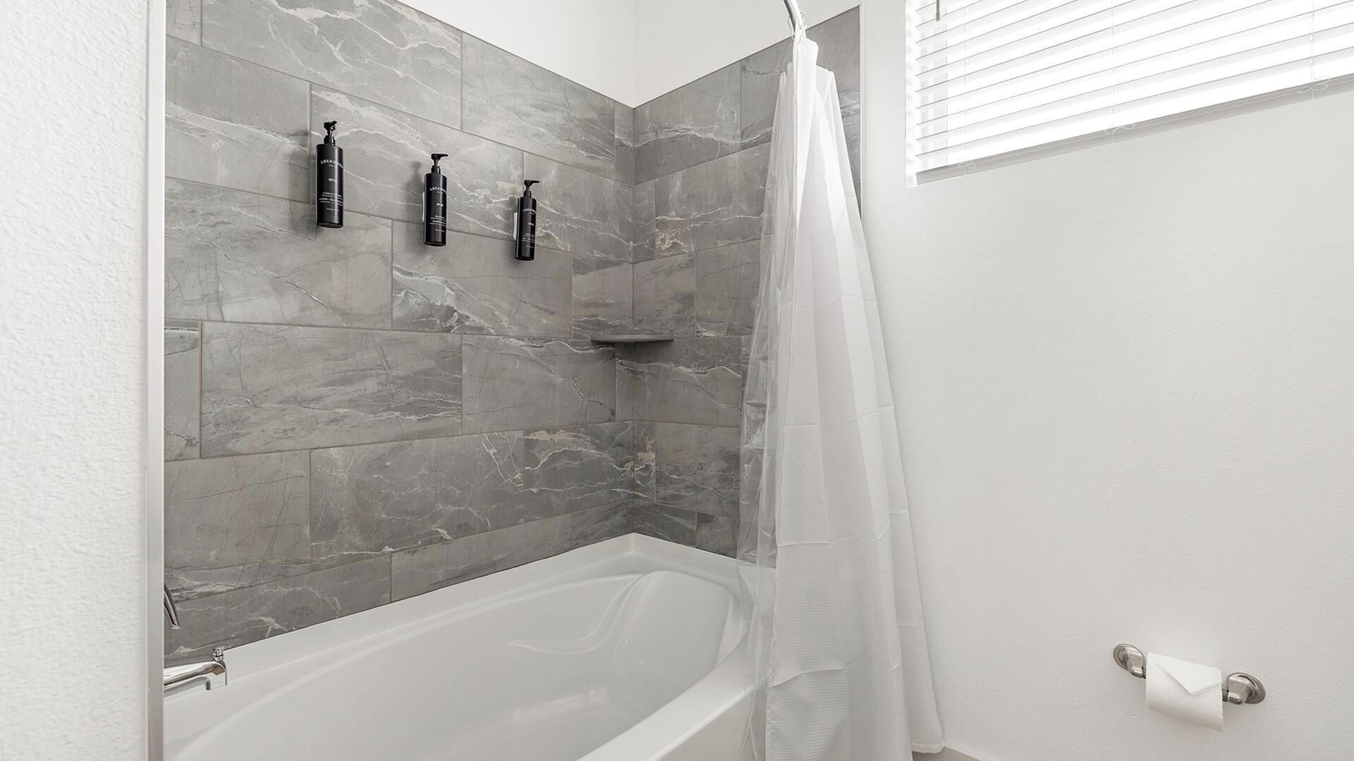 Un baño con bañera, cortina de ducha y tres artículos de tocador en la pared.