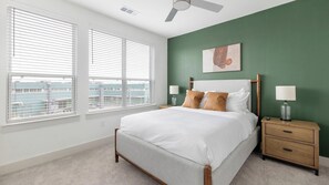 A bedroom with a bed, two bedside tables, a nightstand, a ceiling fan, and a window with blinds. - Landing Amazing 2bd, Courtyard, Pool (Dallas)