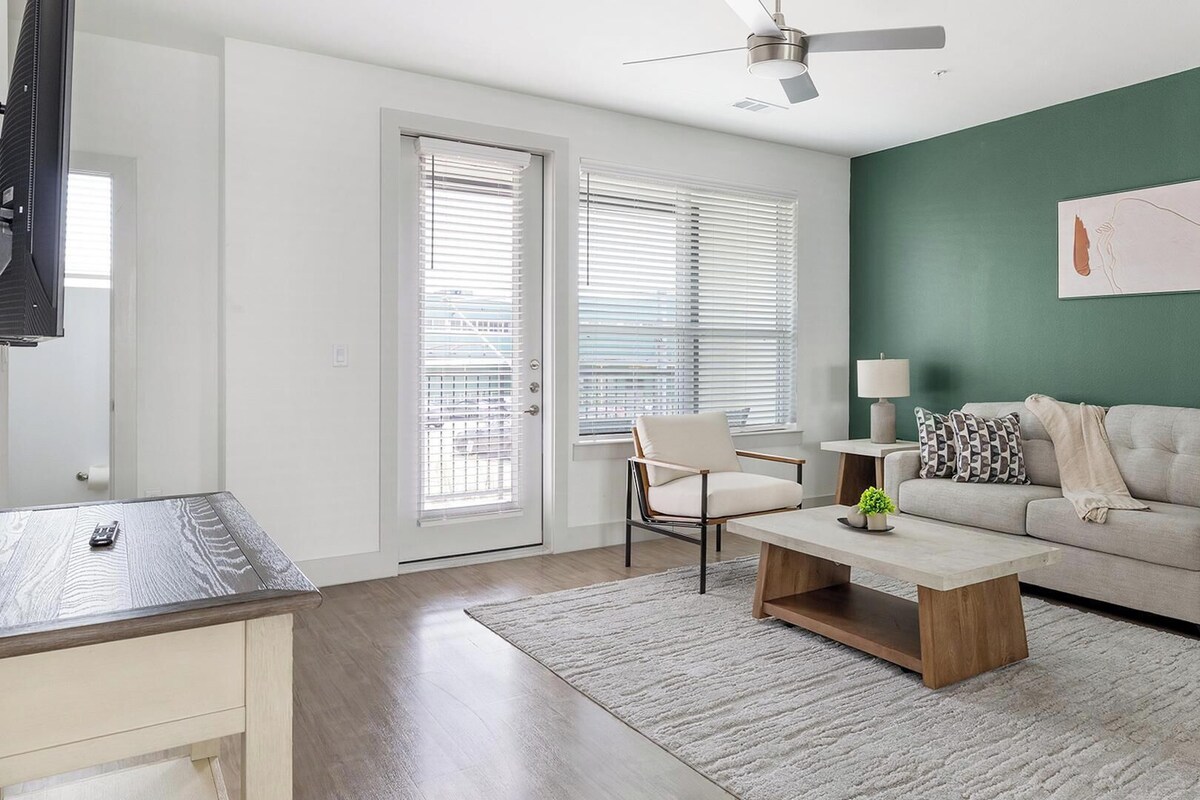 A living room with a sofa, a coffee table, a chair, a TV, and a ceiling fan.