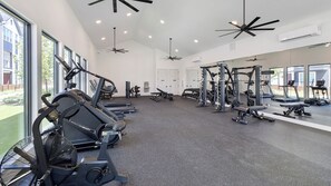 A gym with various exercise equipment, large windows, and ceiling fans. - Landing Amazing 2bd, Courtyard, Pool (Dallas)