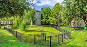 A fenced courtyard with a picnic table, surrounded by trees and a building with multiple windows. - Landing Amazing 1BD in Copperfield (Houston)