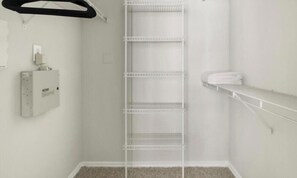 Ein weißes Zimmer mit einer weißen Metallregaleinheit an der Wand, einem weißen Handtuchhalter und einem weißen Elektroverteiler.