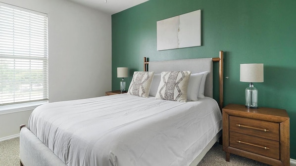 A bedroom with a bed, two nightstands, a lamp, a window with blinds, and a green wall. - Landing Amazing 1BD in Copperfield (Houston)