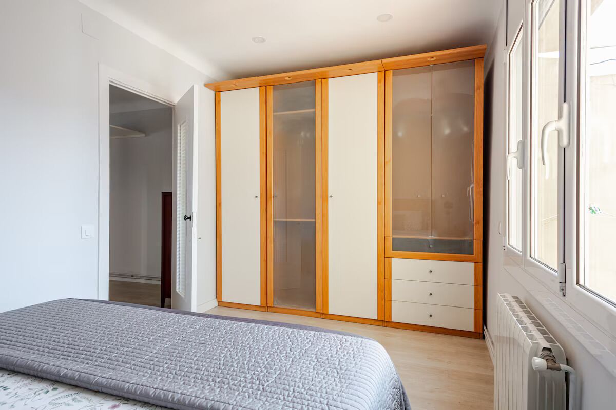 Une chambre à coucher avec un lit, une armoire et une fenêtre.