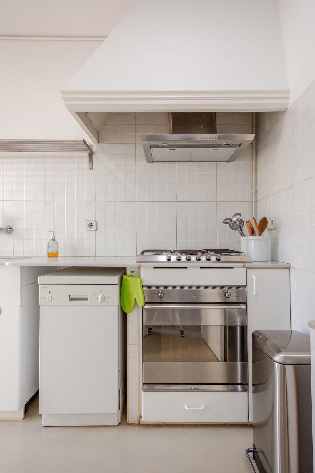 A kitchen with a built-in oven, a dishwasher, and a stainless steel range hood.