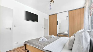 Ein modernes Schlafzimmer mit Bett, Flachbildfernseher, Kleiderschrank und Spiegel.