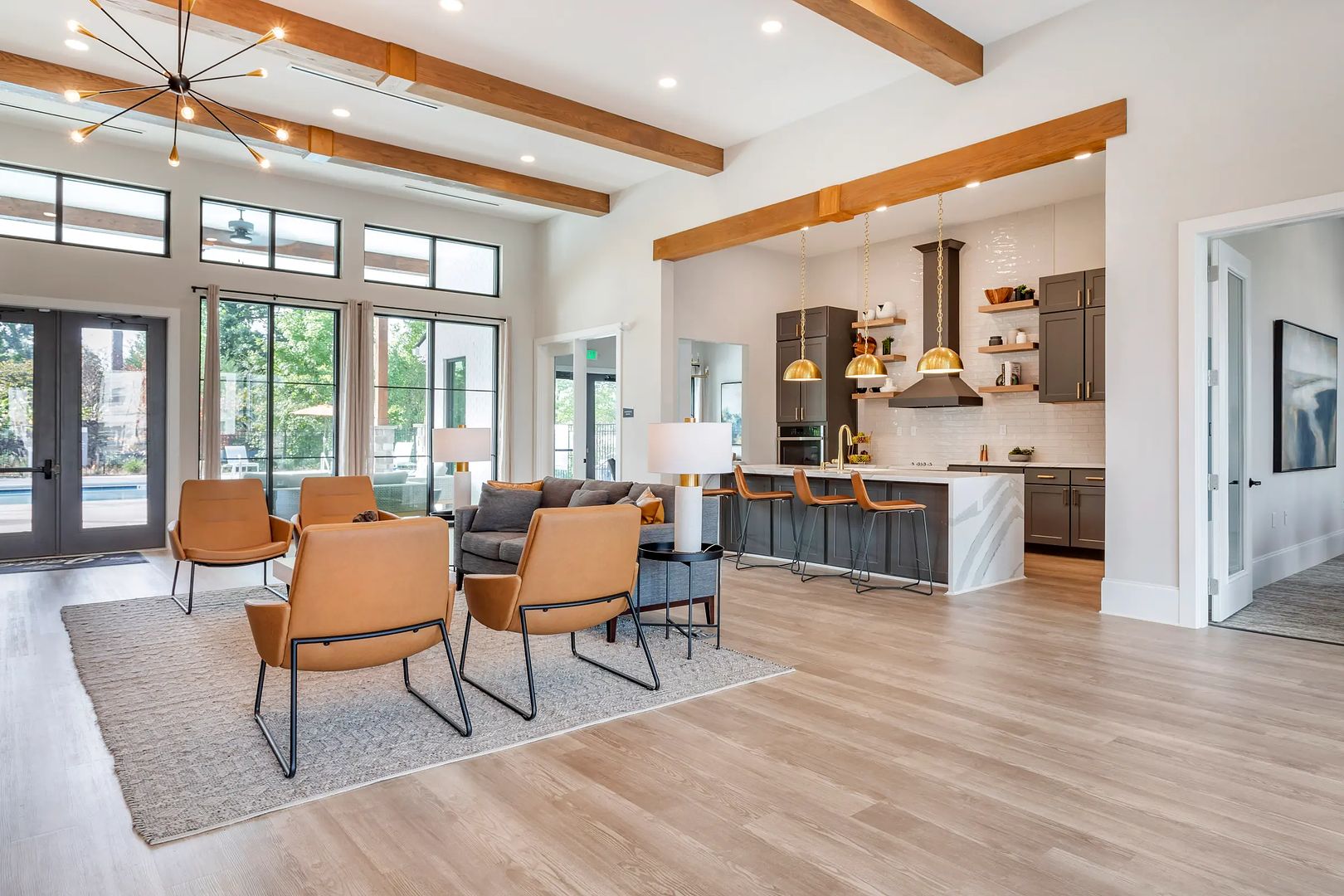 A spacious living area with a dining set, a kitchen with modern appliances, and large windows providing natural light.