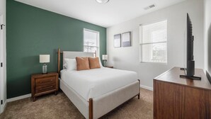 Een slaapkamer met een bed, nachtkastjes, een dressoir en een televisie.