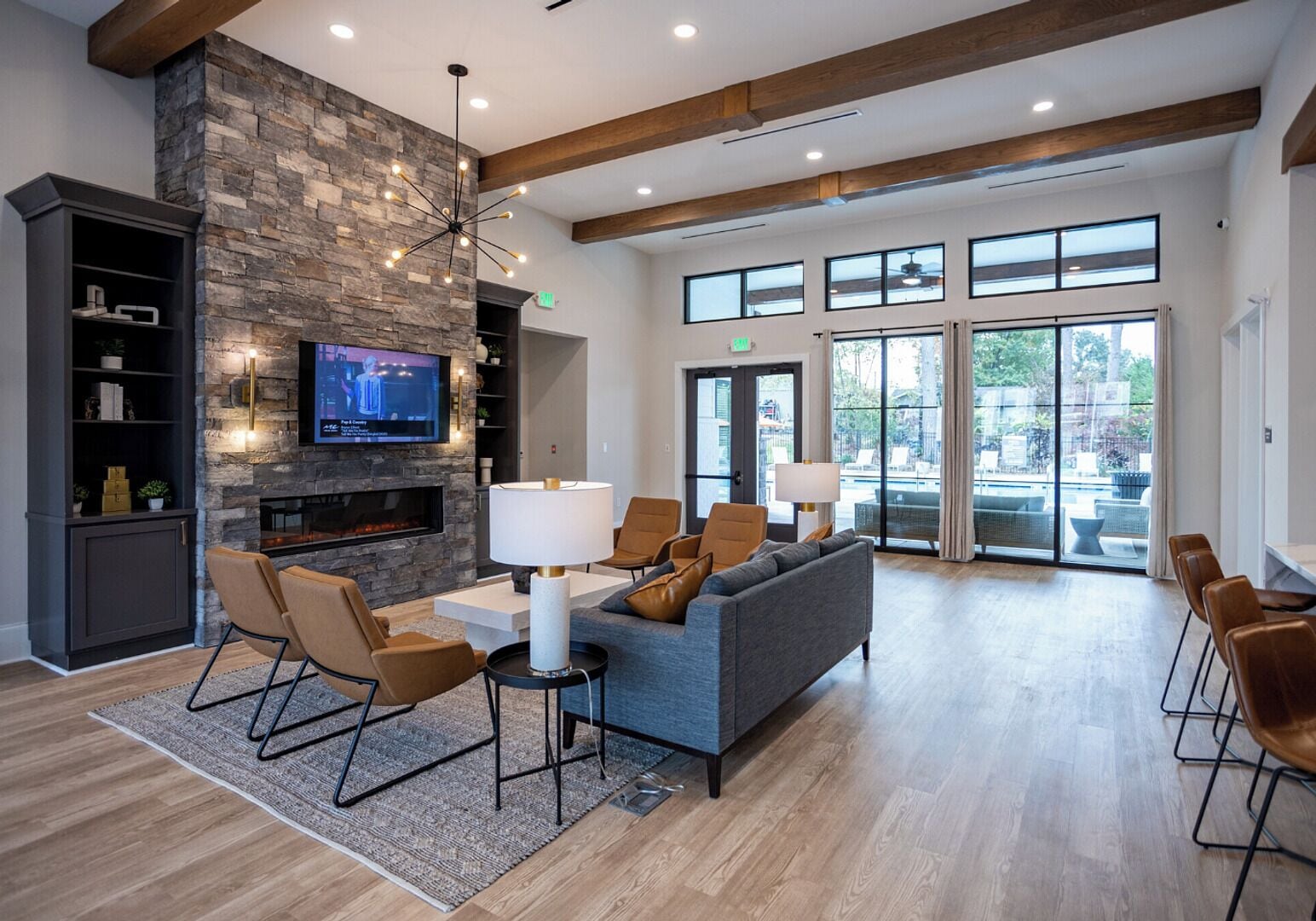 A spacious lobby with a stone fireplace, comfortable seating, a television, and large windows offering views.