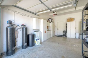 Eine Garage mit zwei großen, schwarzen Sauerstoffflaschen, einer weißen Tür und einem Metallregal.