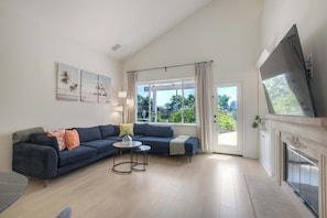 A modern living room with a sofa, a coffee table, and a fireplace. - Brick & Beach Family Retreat (Carlsbad)