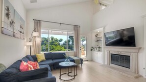 Un salón amplio con una televisión grande, una chimenea y un balcón con cortinas.