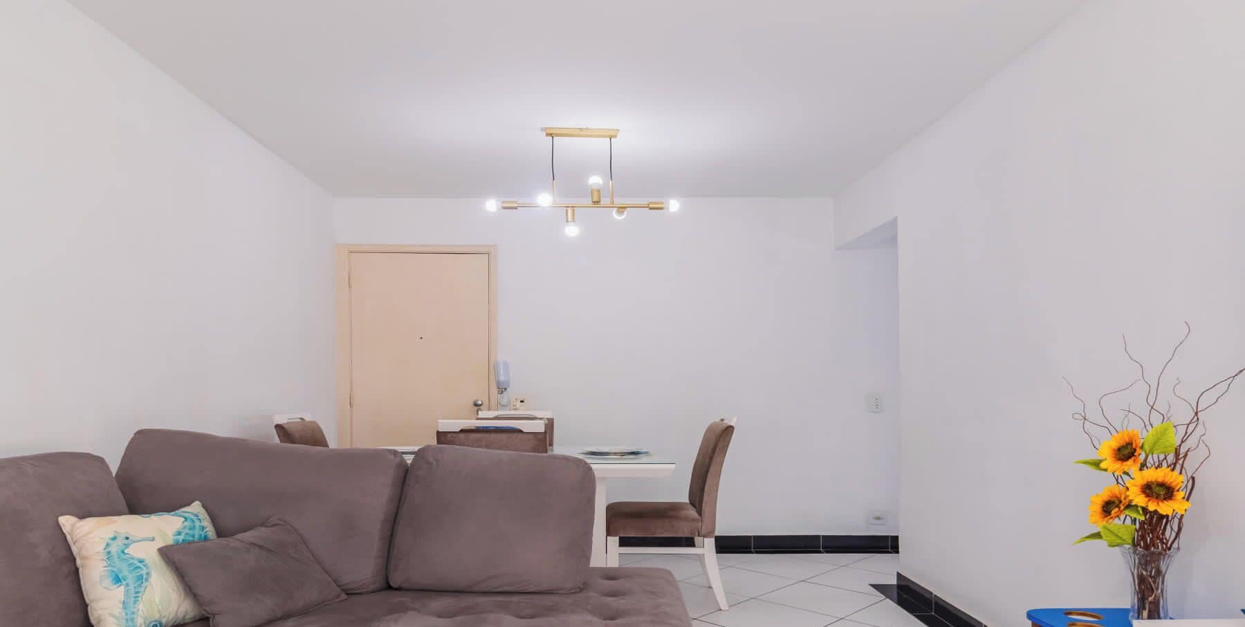 A modern living room with a sofa, a dining table, and a chandelier.