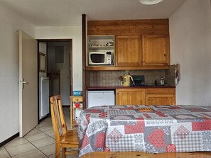 Eine kleine Küche mit Holzschränken, einer Mikrowelle und einem Kühlschrank.