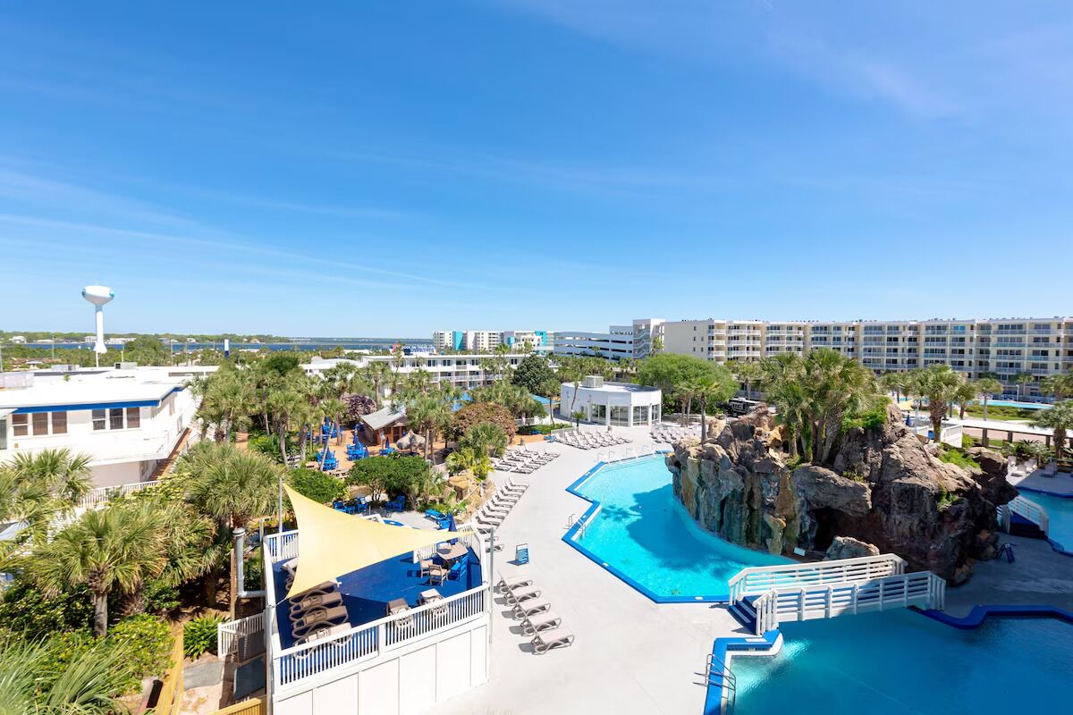 A resort with a large pool, palm trees, and a view of the ocean.