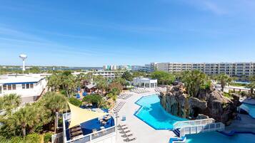 A resort with a large pool, palm trees, and a view of the ocean.