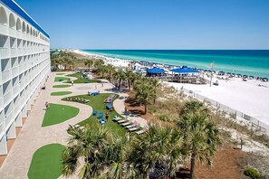 A resort with a beach view, a pool area, and a large building with a white facade.
