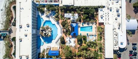 Un edificio grande con un patio central, piscina y zona de estacionamiento.