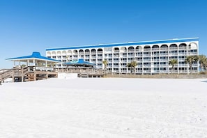 A large hotel with multiple balconies and a beach bar area.