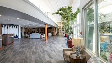 Eine geräumige Lobby mit gewölbter Decke, einem Empfangstresen, einer Sitzecke und großen Fenstern mit Blick ins Freie.