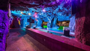 Ein Innenbereich mit Schwimmbecken, Felsformationen und einer Bar.