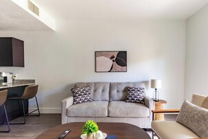 A modern living room with a sofa, a coffee table, a lamp, and a painting on the wall.