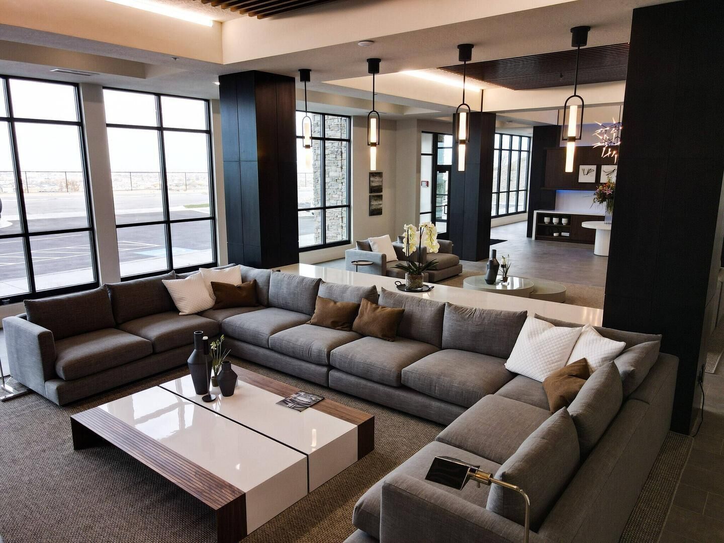 A modern living room with a sectional sofa, a coffee table, and pendant lighting.