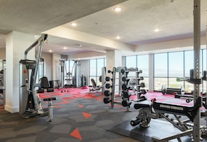 A gym with various exercise equipment, large windows, and a red carpeted floor. - Landing Modern 1bd, Gym (Draper)