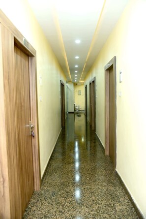 A hallway with wooden doors, a polished granite floor, and recessed lighting.