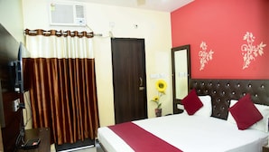 Habitación de hotel con cama, televisión, escritorio y pared decorada con motivos florales.