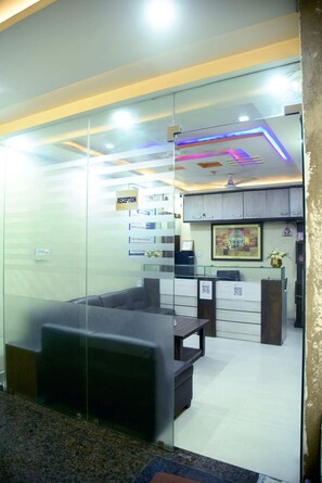A reception area with a reception desk, a seating area with a sofa, and a wall-mounted clock.